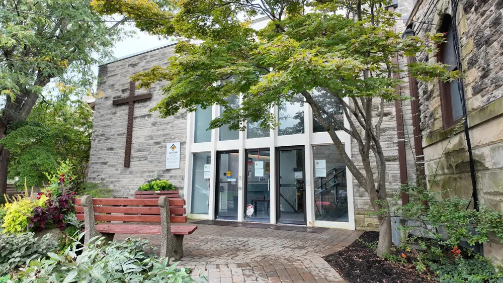 The entrance to the office building on Clifton Avenue, with a bench and trees out front