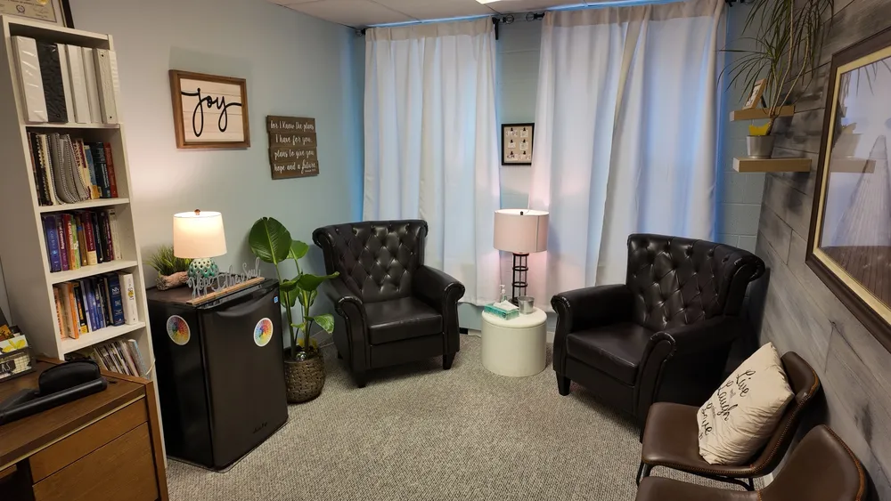 The office bookshelf, lamp, and armchairs by the window